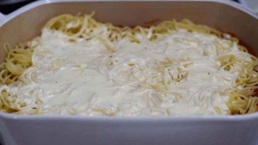 the layer of alfredo sauce poured over cooked spaghetti noodles for thsi ultimate baked spaghetti recipe