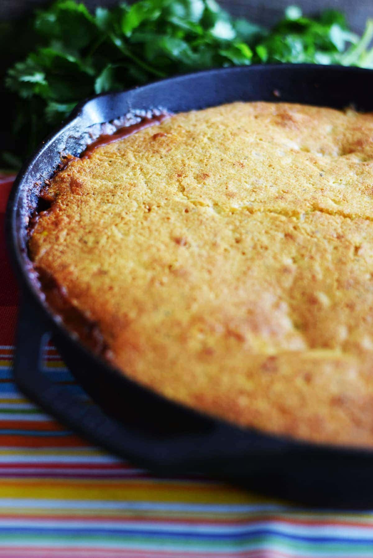 a closeup of this golden jalapeno cornbread taco pie inside of a black cast iron skillet