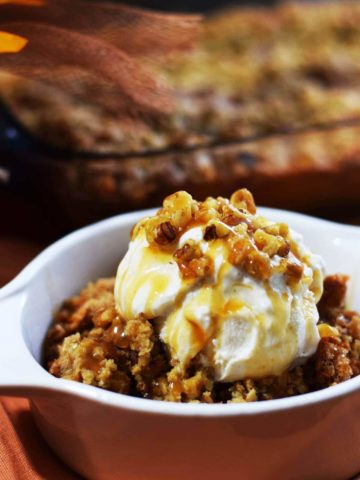a side view of a serving of this caramel pumpkin spice crunch cake topped with vanilla ice cream