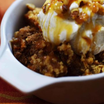 a closeup of a serving of this caramel pumpkin spice crunch cake topped with vanilla ice cream and caramel sauce