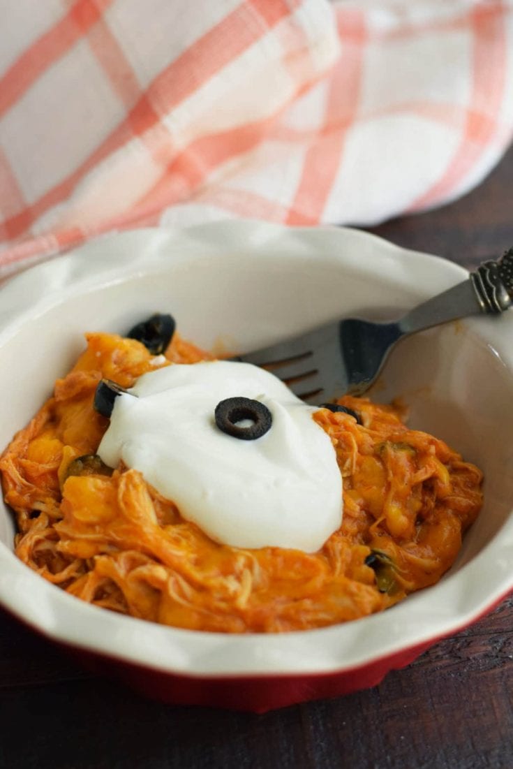 a serving of this crock pot chicken enchilada casserole topped with sour cream and black olives