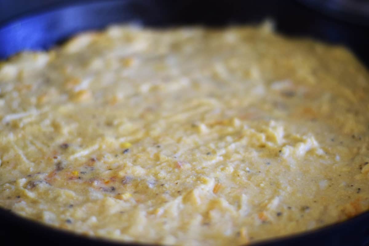 a closeup of the uncooked jalapeno cornbread crust for this taco pie recipe inside of a black cast iron skillet