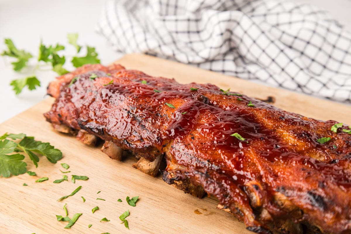 A rack of baby back ribs on a cutting board.