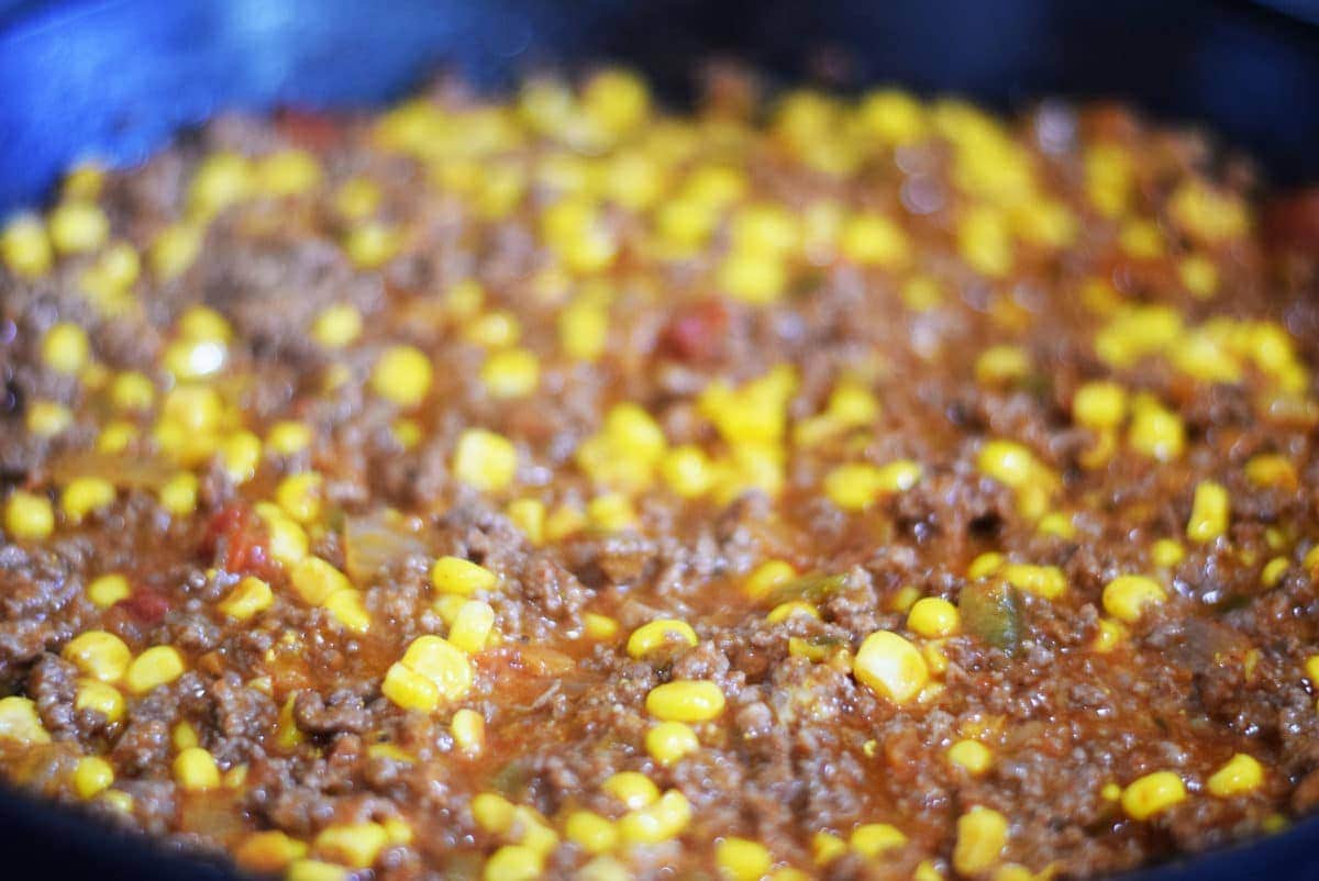 a closeup of the ground beef and vegetable filling for this jalapeno cornbread taco pie inside of a black cast iron skillet