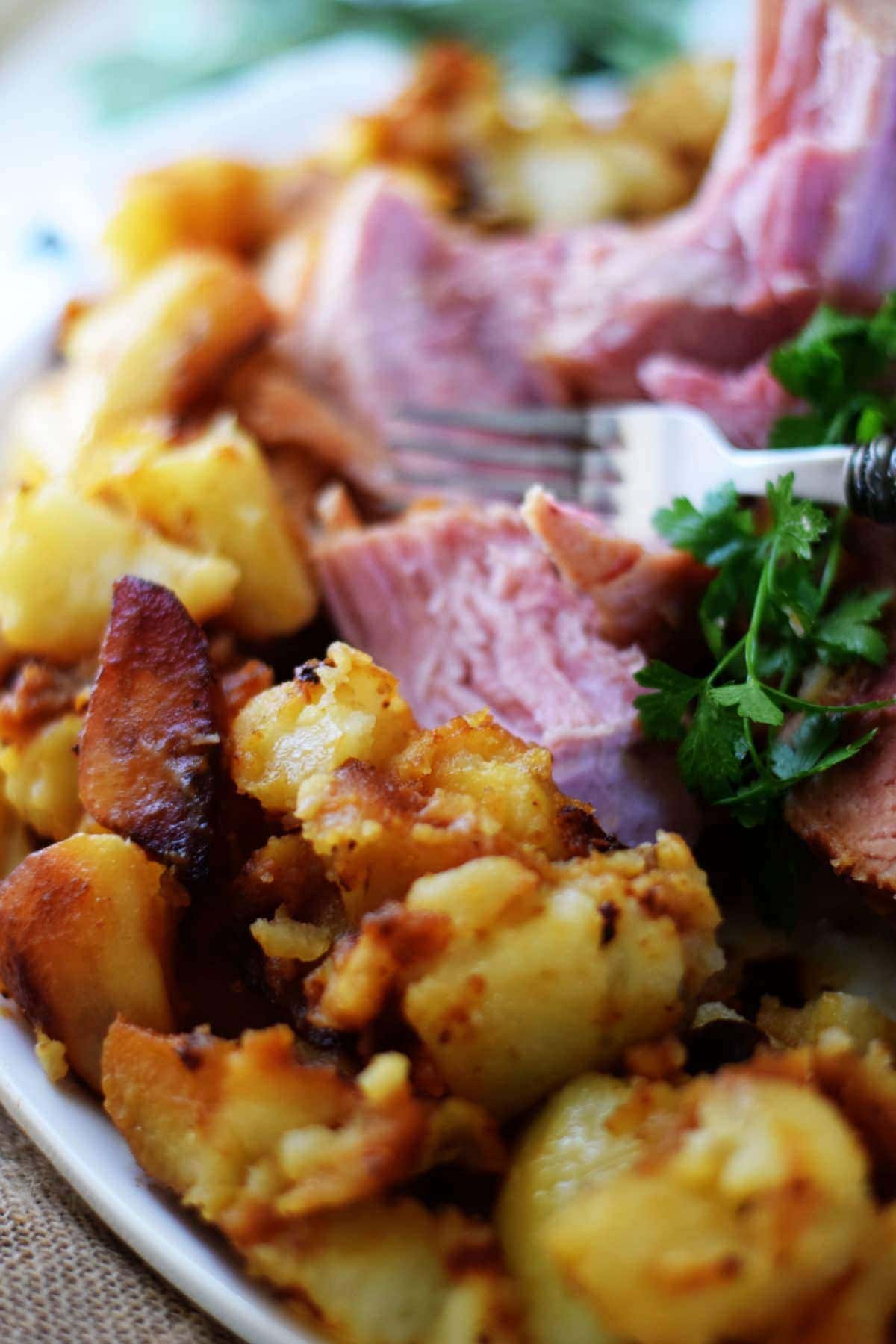 Plated Ham sliced with potatoes with fork and parsley