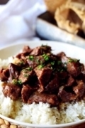 A white plate filled with white rice and this instant pot beef tips recipe aka pressure cooker beef tips garnished with chopped parsley