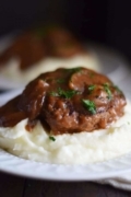 A closeup of a serving of this slow cooker salisbury steak over a bed of creamy instant pot mashed potatoes