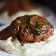 A closeup of a serving of this slow cooker salisbury steak over a bed of creamy instant pot mashed potatoes