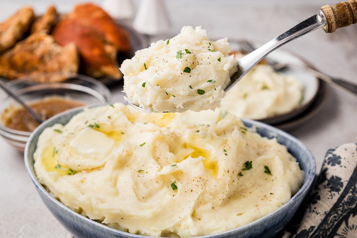 Instant Pot Mashed Potatoes Removing a serving of mashed potatoes with a serving spoon from a bowl.