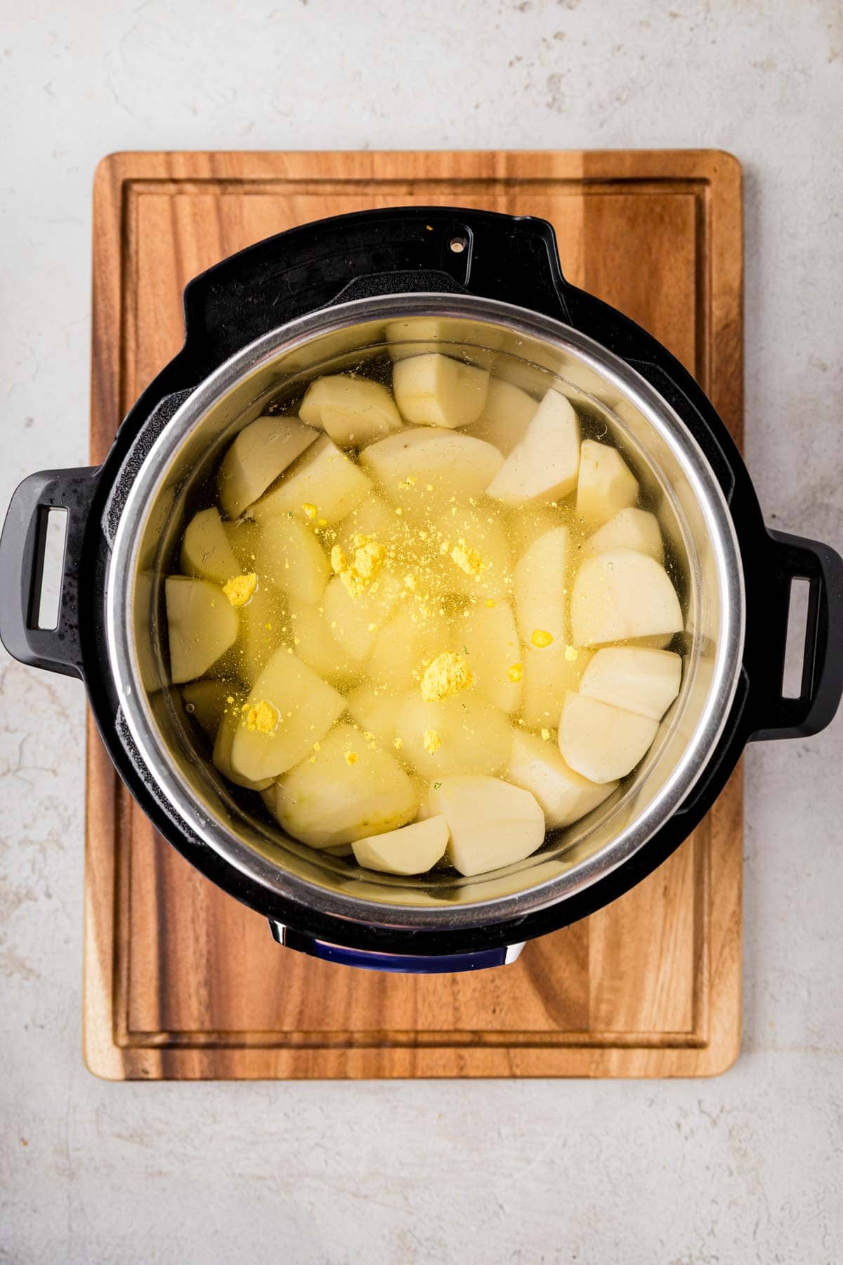 Chicken bullion and salt added to Instant pot filled with water and peeled potatoes.