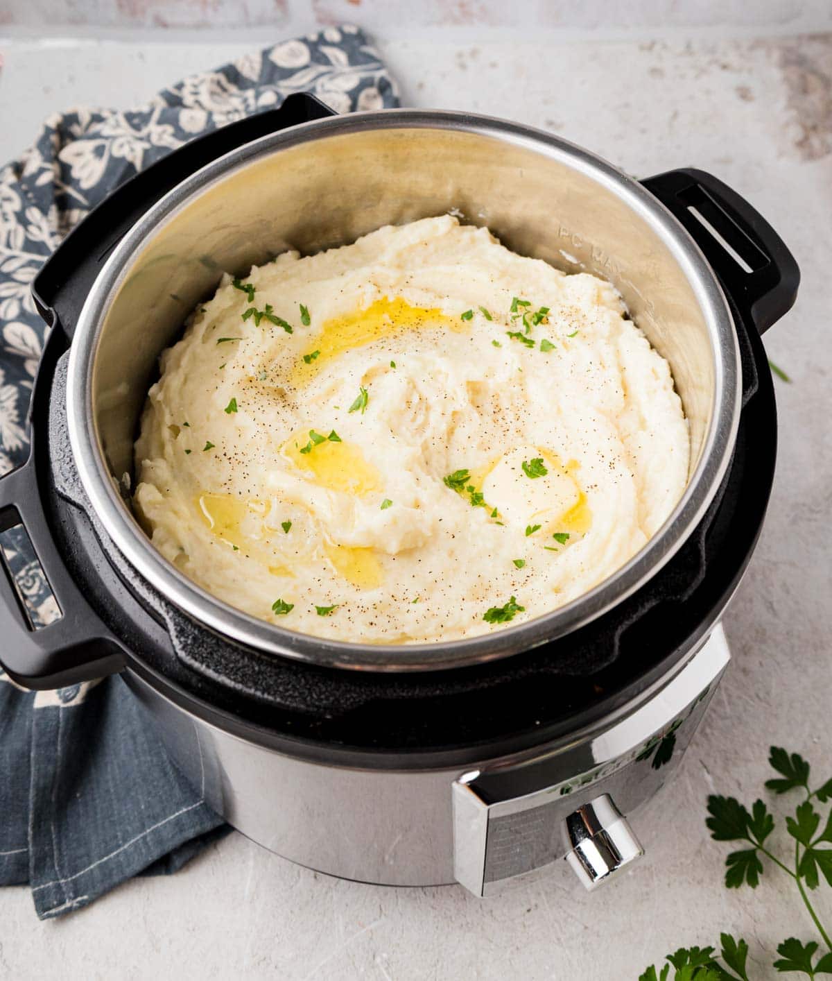 An Instant Pot filled with creamy mashed potatoes and garnished with melted butter and parsley.