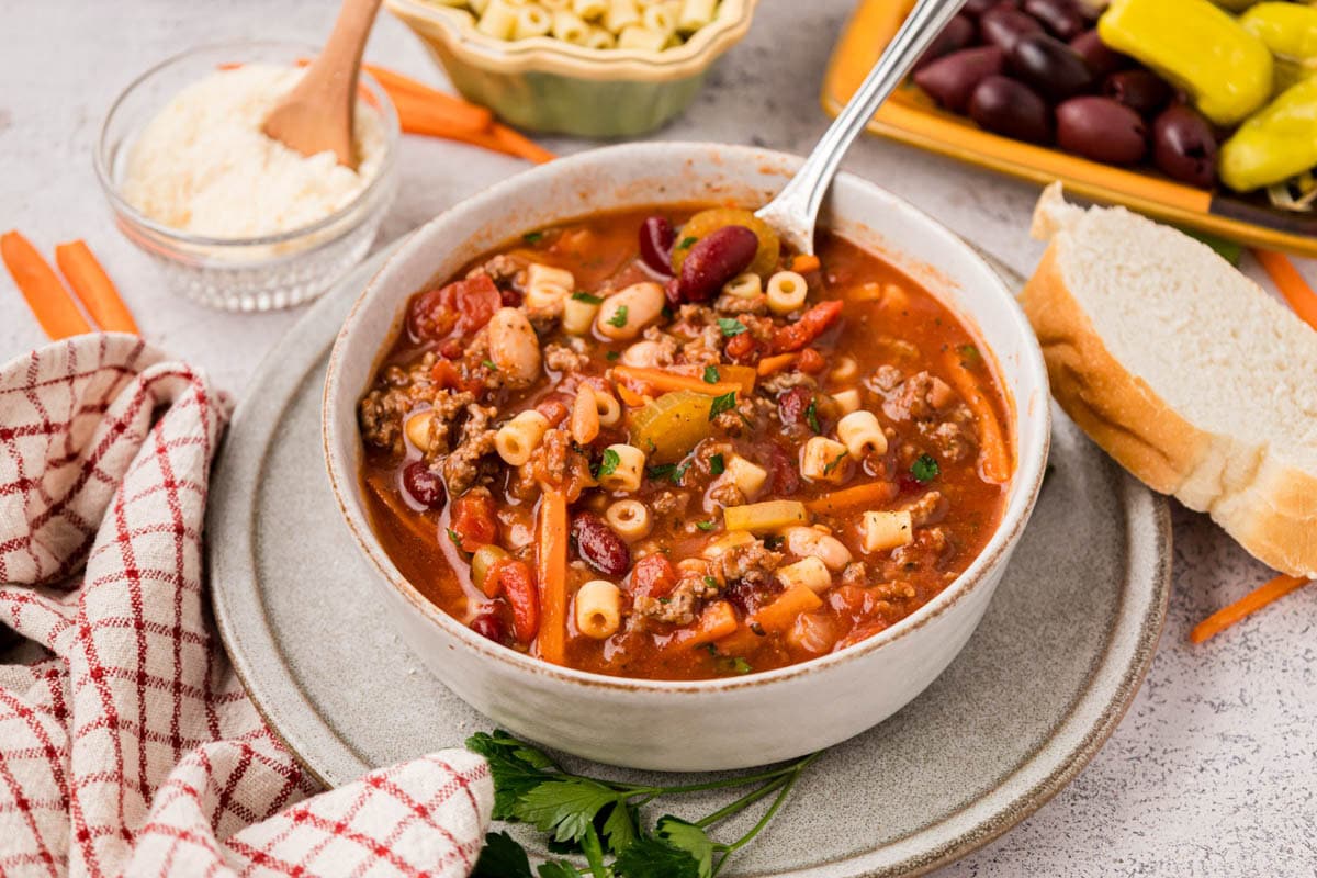 A bowl of copycat olive garden pasta fagioli soup in a bowl with a slice of bread on the side.
