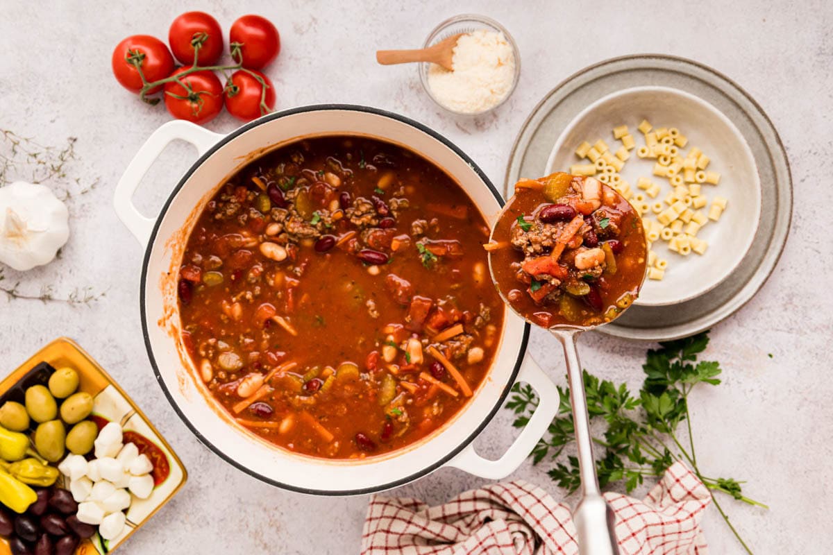 Ladling pasta fagioli soup into a bowl with ditalini pasta.