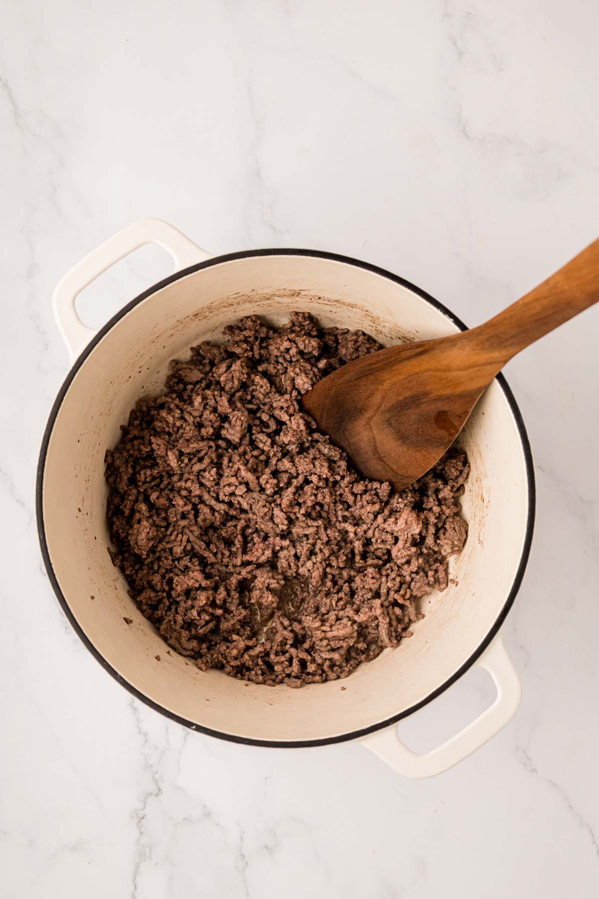 Ground beef cooked and crumbled in a dutch oven.