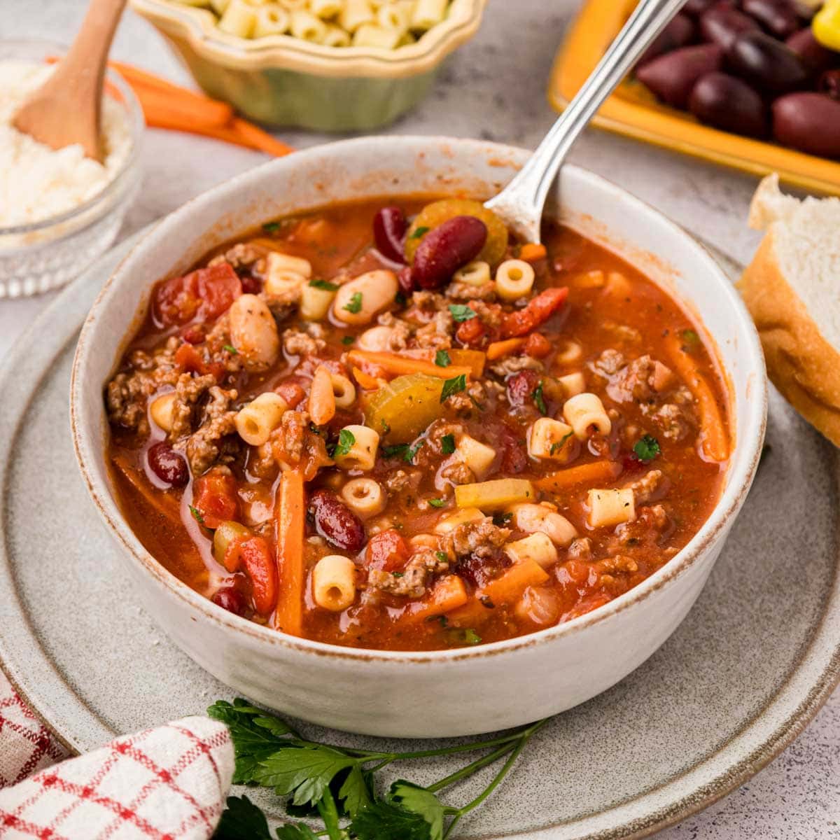 A bowl of pasta fagioli soup with a spoon removing a bite.
