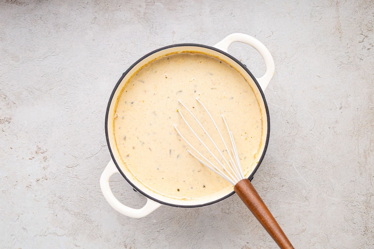 White chicken chili being stirred to incorporate the sour cream and whipping cream.