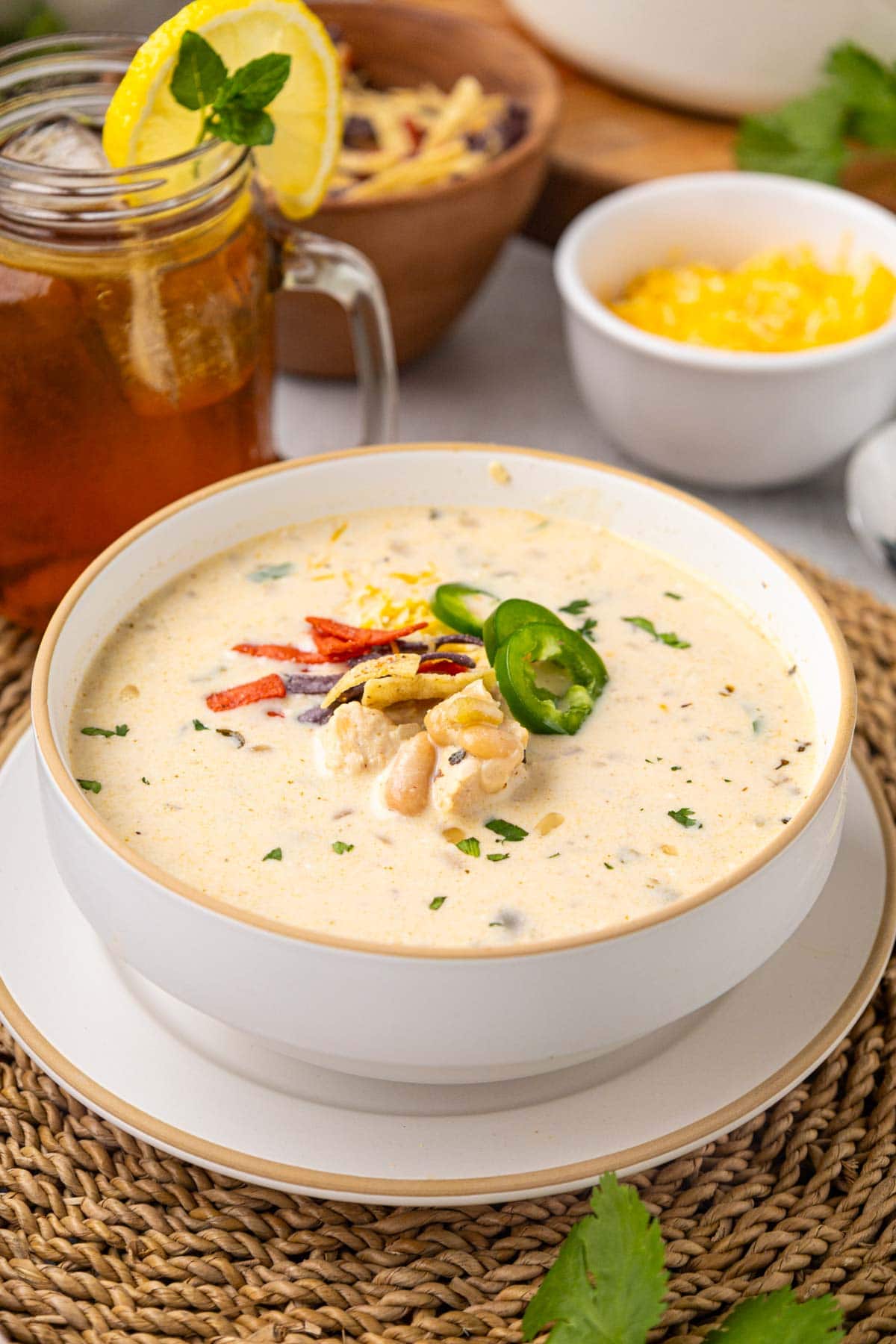 A bowl of white chicken chili topped with slice jalape&ntilde;os, cheese, and toritlla strips.