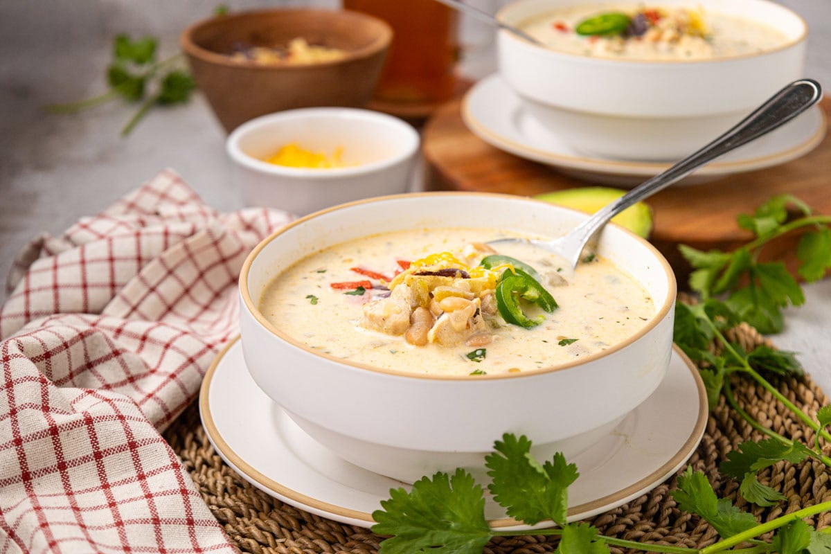 A bowl of white chicken chili topped with slice jalape&ntilde;os, cheese, and tortilla strips.