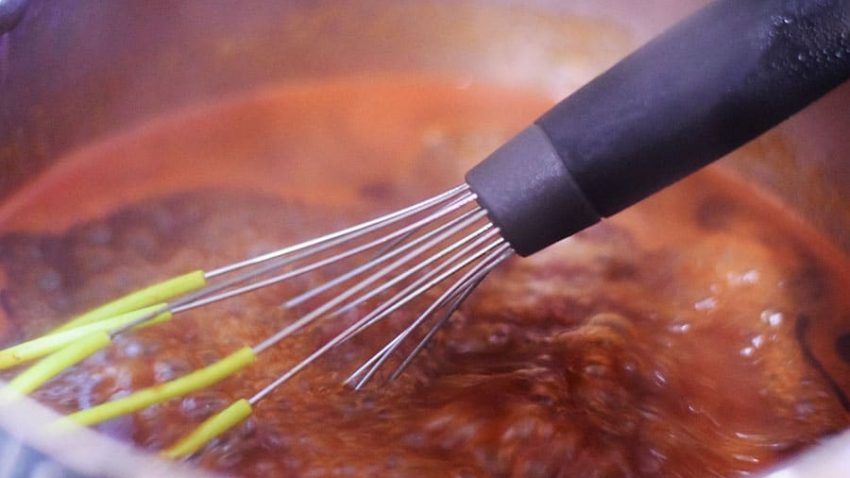 a whisk mixing together the homemade barbecue sauce for this slow cooker beef brisket