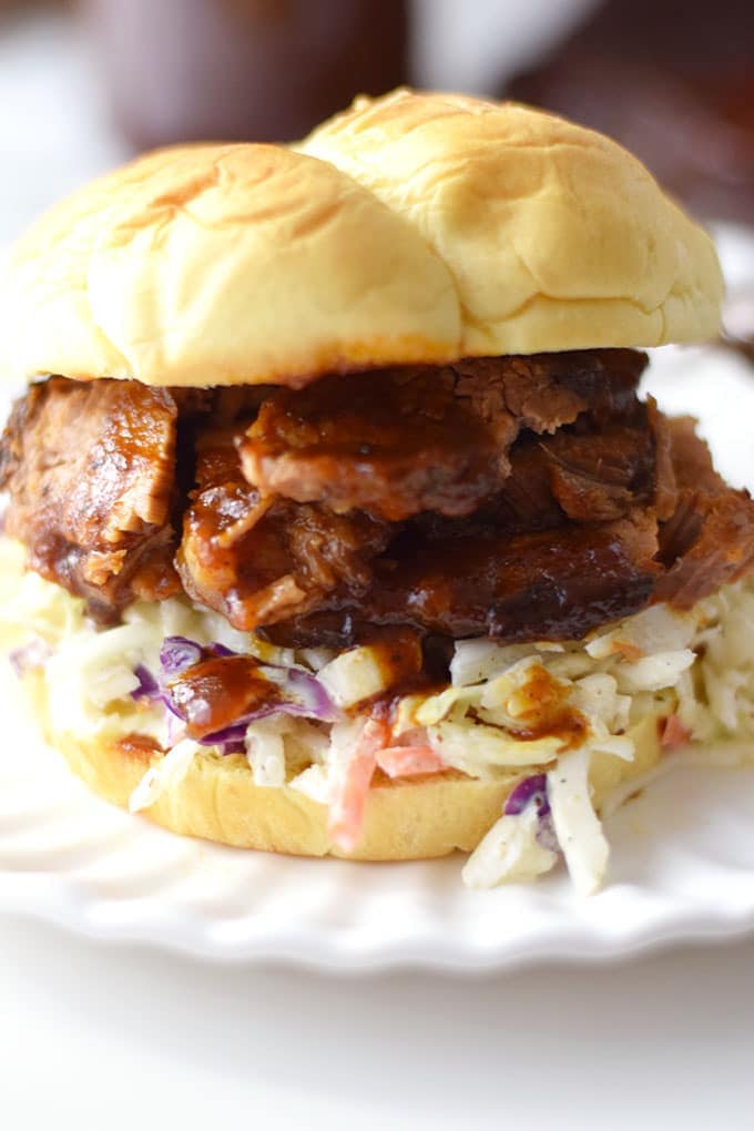 a slow cooker beef brisket sandwich with barbecue sauce and coleslaw