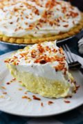 a closeup of a slice of this coconut cream pie with toasted coconut on a white plate