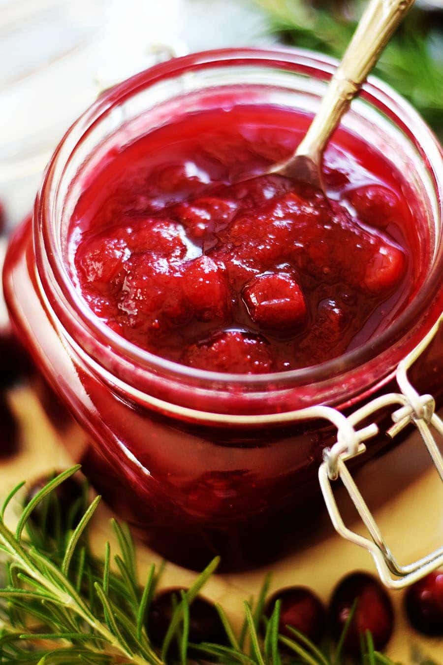 a glass jar filled with this bright red crock pot cranberry sauce