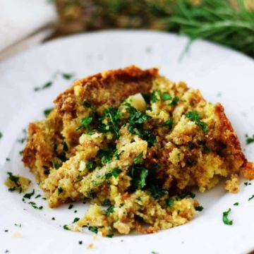 a serving of this crock pot cornbread dressing on a white plate garnished with chopped parsley