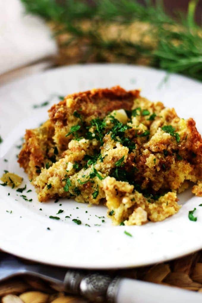 a serving of this easy cornbread dressing on a white plate garnished with chopped parsley