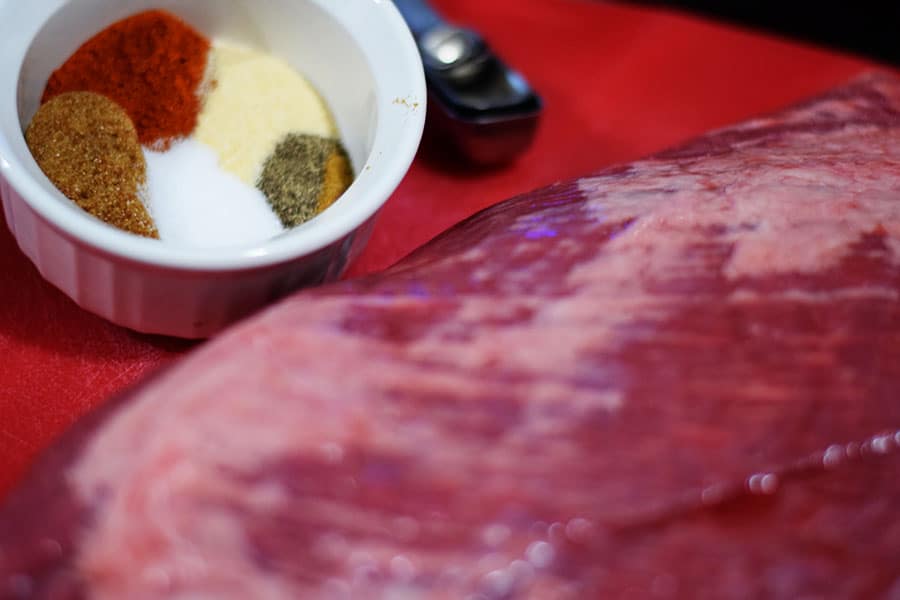 a bowl of spices and a large raw beef brisket for this slow cooker beef brisket recipe