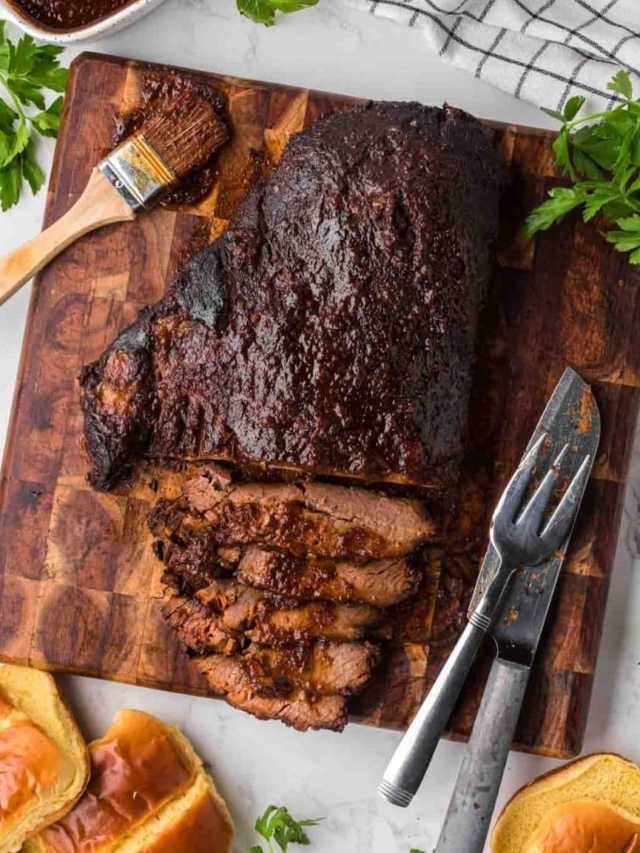 A look from the top of a cutting board with the brisket sliced and slathered with BBQ sauce