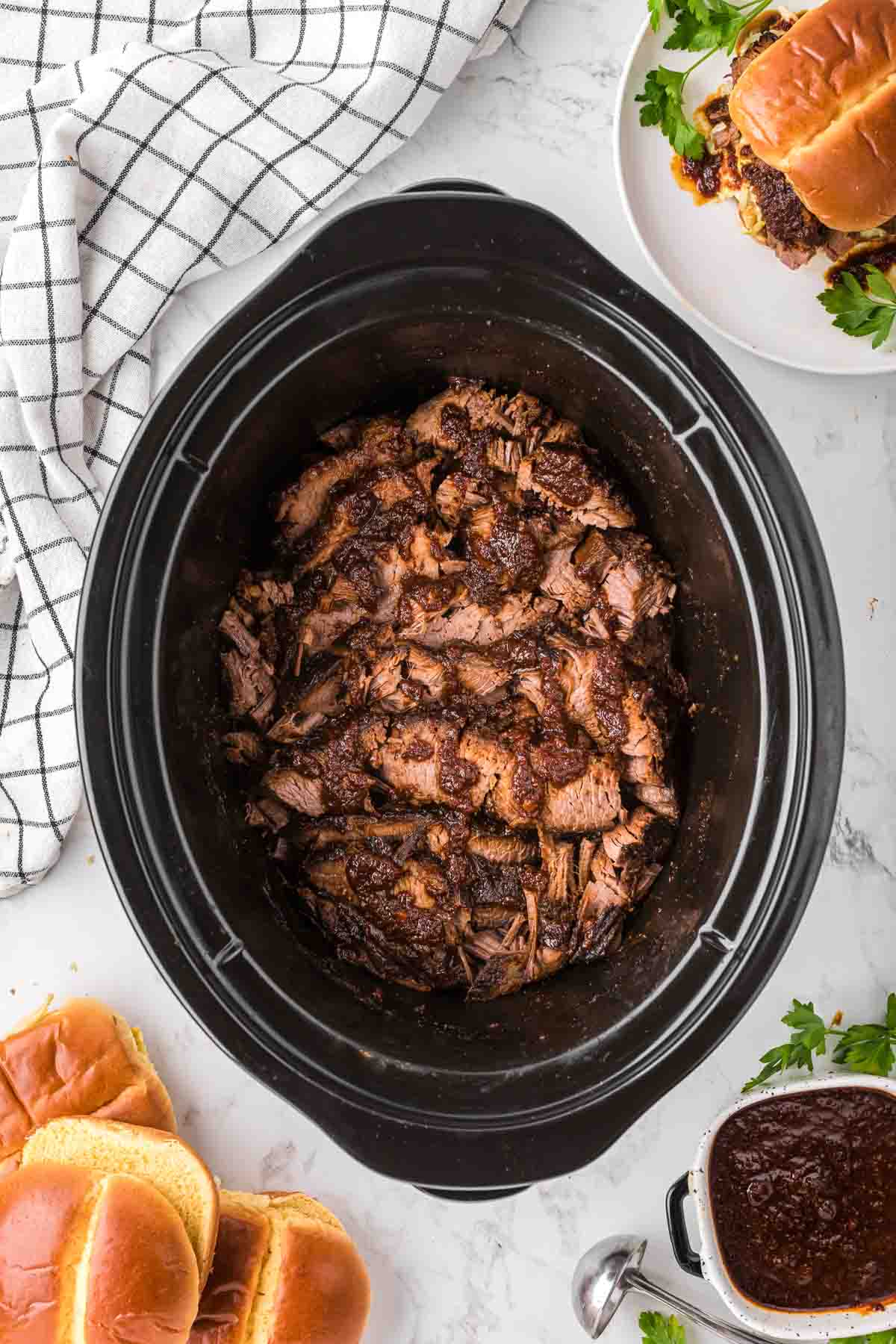 Sliced slow cooker beef brisket placed back in the crock pot after being sliced.