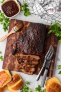 A look from the top of a cutting board with the brisket sliced and slathered with BBQ sauce