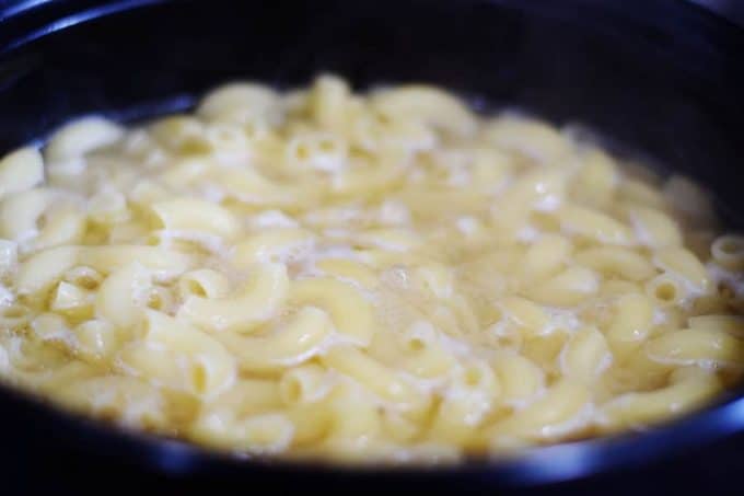 macaroni noodles boiling in a pot on the stovetop to be used this easy macaroni and cheese recipe