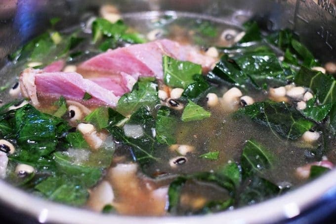 a closeup of this instant pot black eyed pea and collard greens soup with bacon and broth