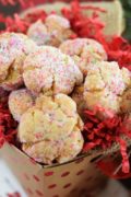 several peanut butter fudge cookies with sprinkles in a gift box with red packing paper