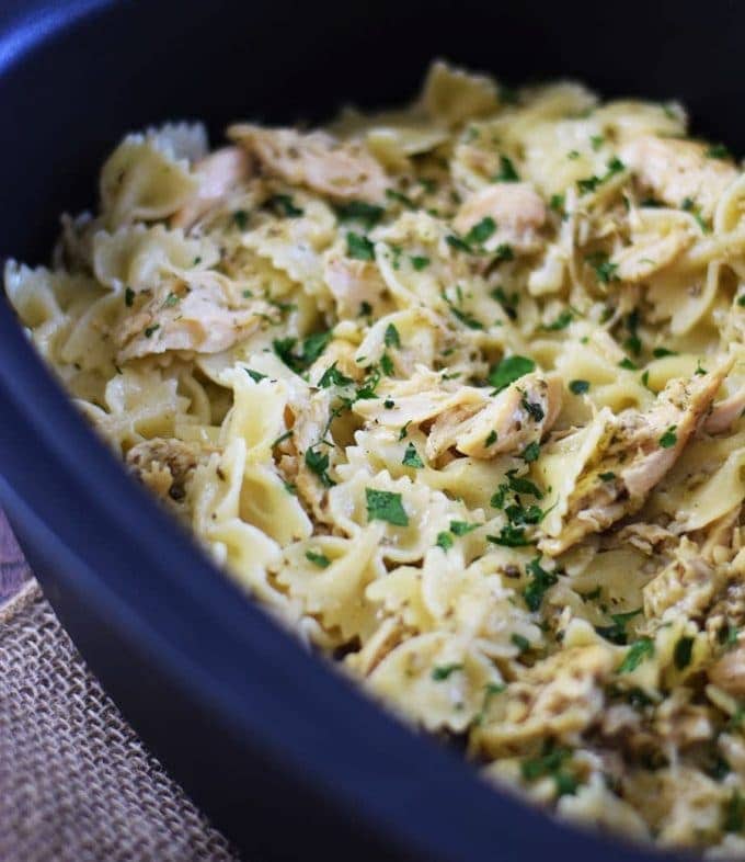 a casserole dish filled with this slow cooker cheesy chicken pesto pasta