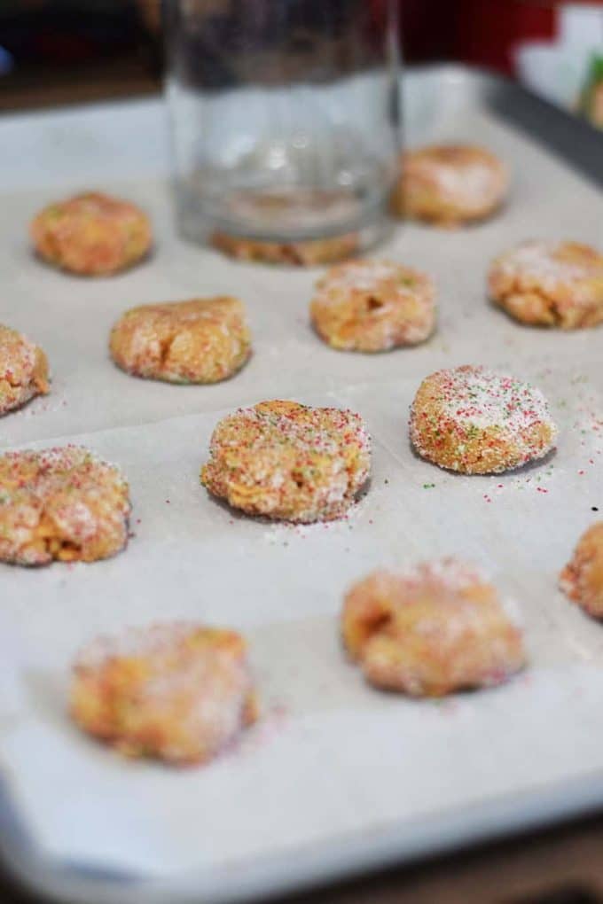 several peanut butter fudge cookies with sprinkles on a lined cookie sheet ready to be baked