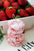 A stack of my Strawberry Cake Mix Cookies wrapped in Christmas twine with a basket of strawberries in the background