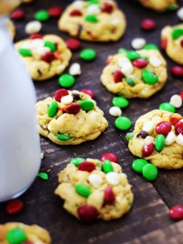 Several Christmas chocolate chip cookies with red, white, and green mini m&m candies, aka Santa's chocolate chip cookies