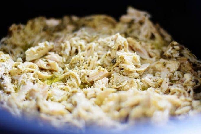 shredded chicken on top of pesto for this slow cooker cheesy pesto chicken pasta