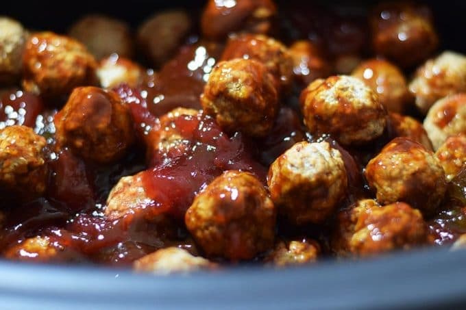 a closeup of these slow cooker strawberry jalapeno bbq meatballs in a crock pot with barbecue sauce
