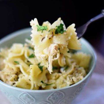 a light blue bowl filled with this slow cooker cheesy pesto chicken pasta