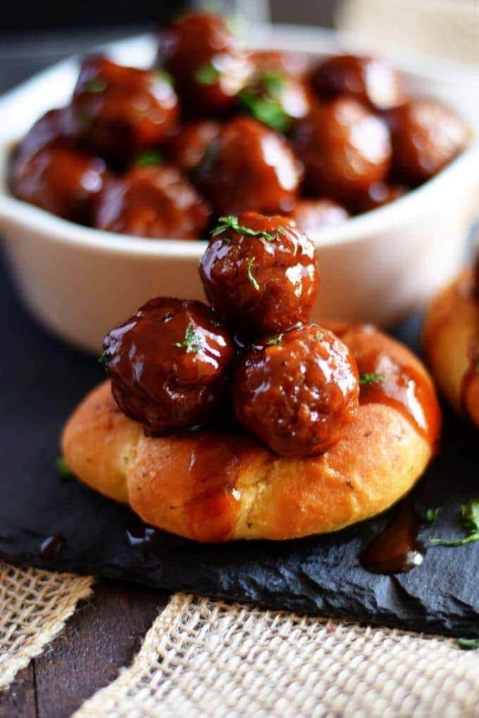 A close up of three slow cooker strawberry jalapeño bbq meatballs on top of a piece of bread