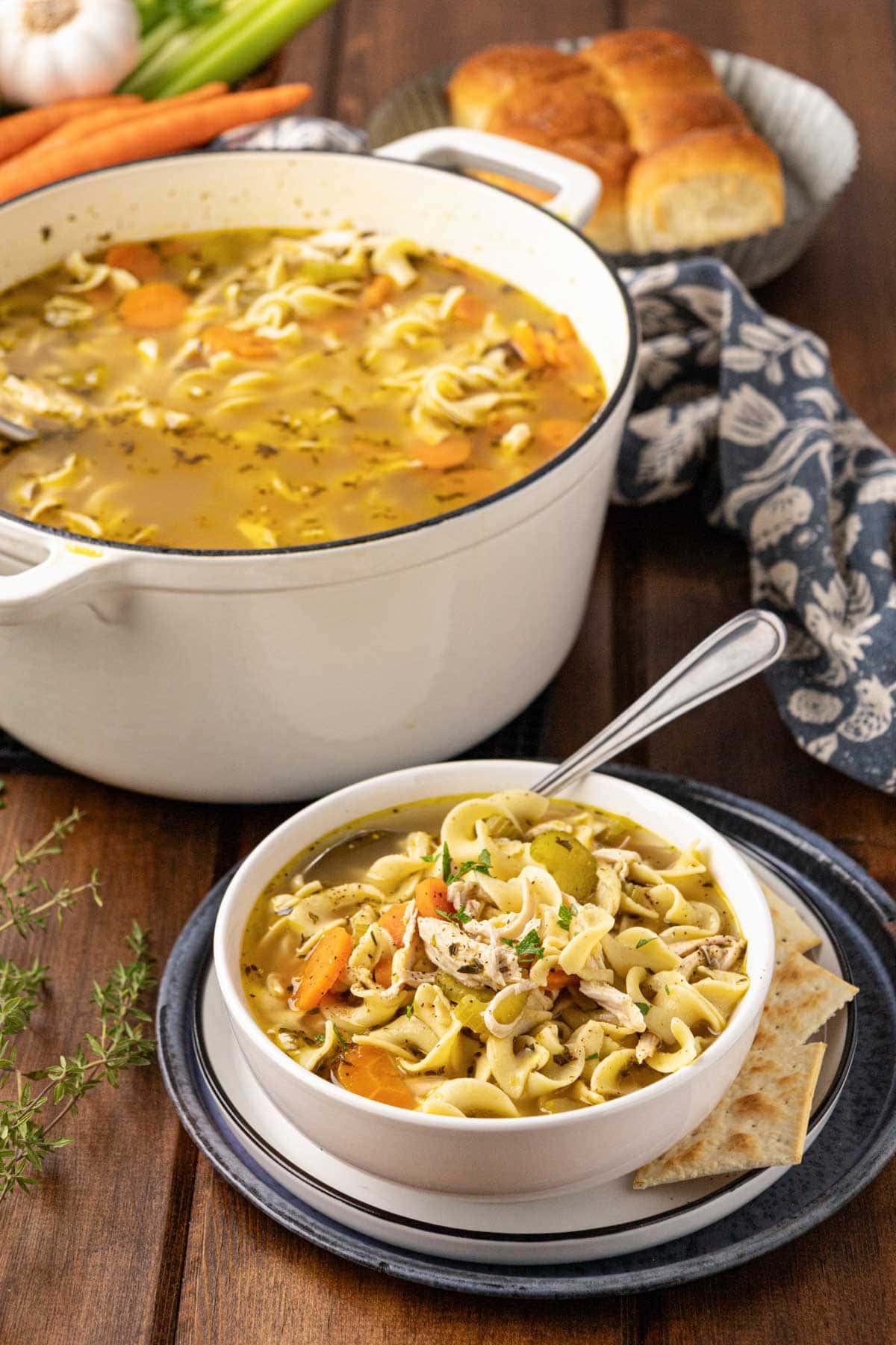 A bowl of chicken noodle soup made with rotisserie chicken with the pot of soup in the backround.