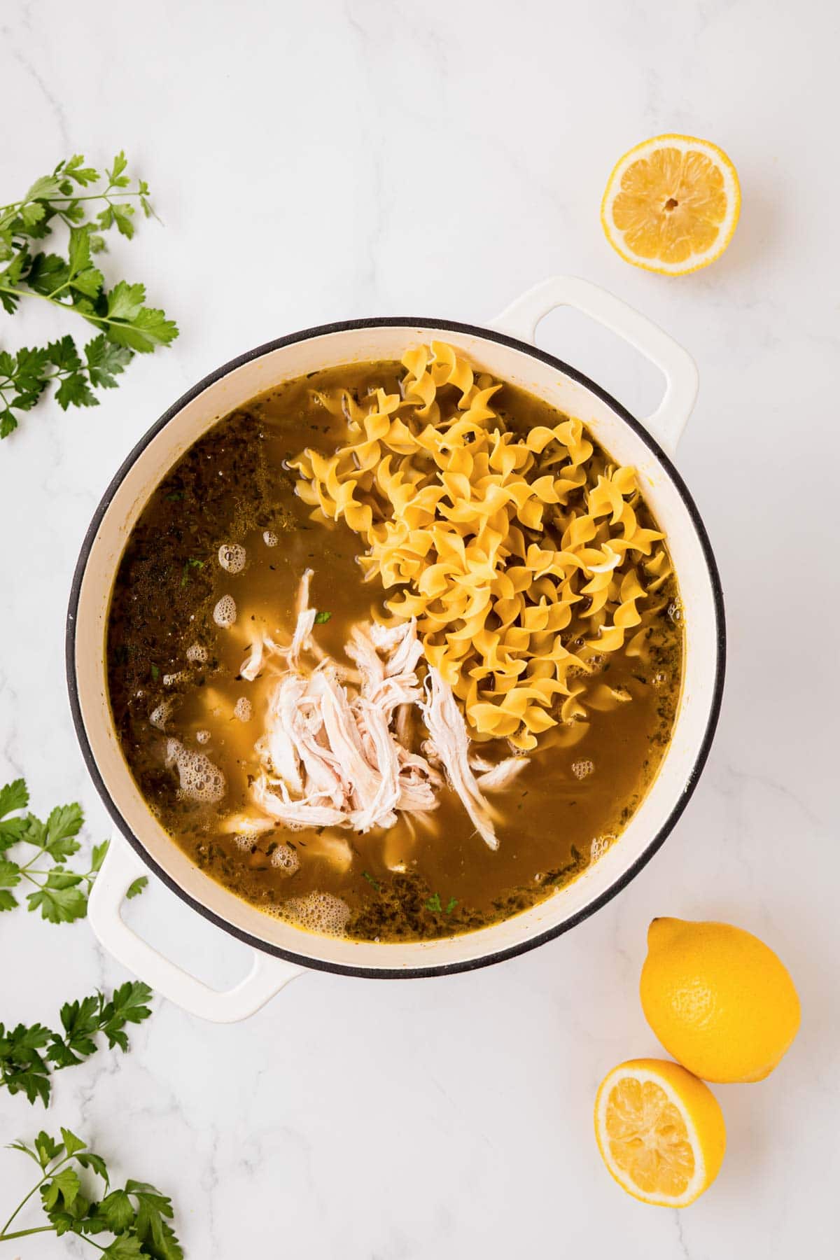 Shredded chicken and noddles added to soup pot.