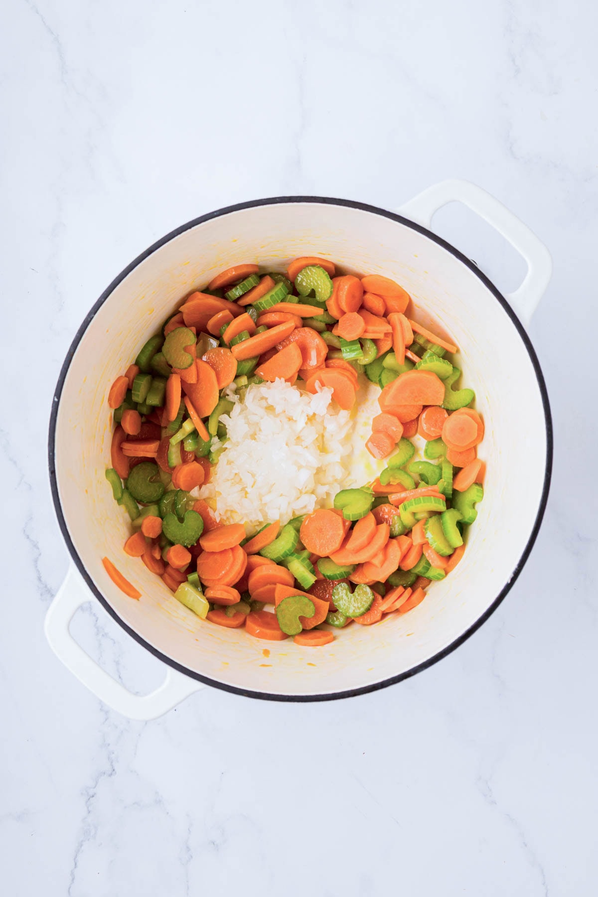 Sautéed carrots and celery with onion added to a dutch oven.