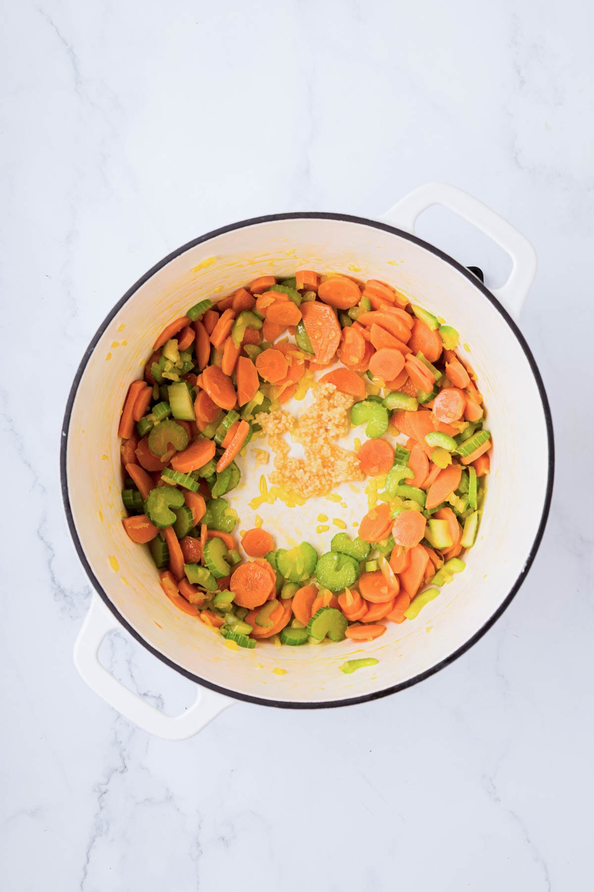 Sautéed carrots and celery, onion with garlic added to a dutch oven.