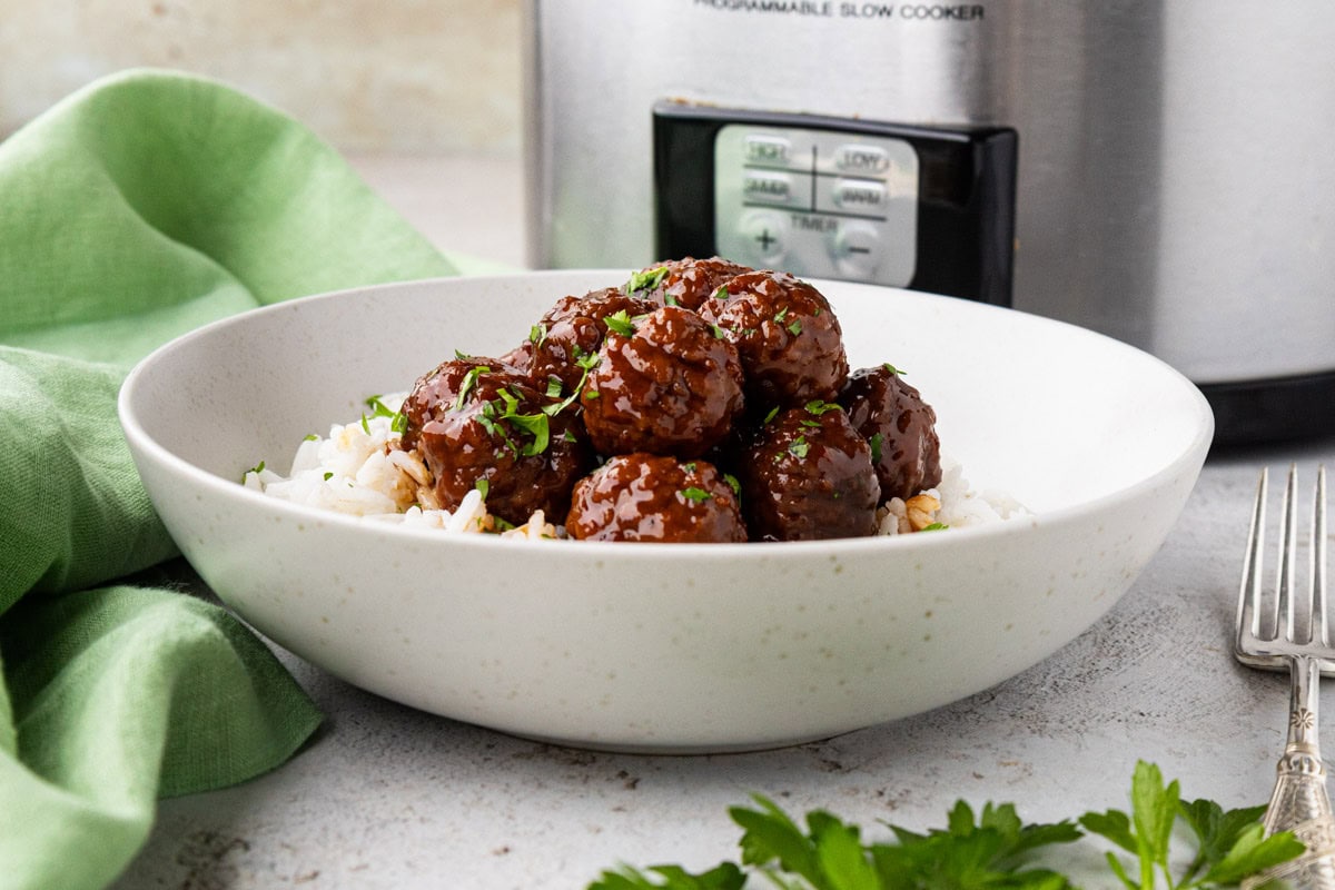 Jelly meatballs served over rice in a white bowl.