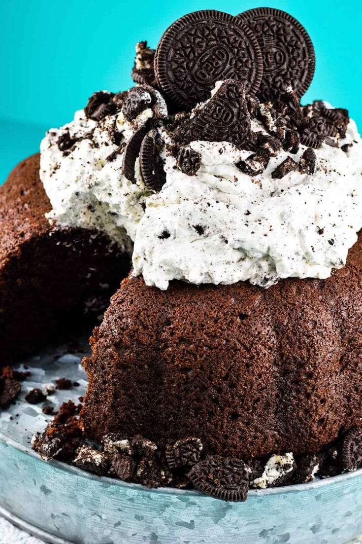 Chocolate Bundt Cake with Oreo Whipped Cream Icing on a rustic cake stand
