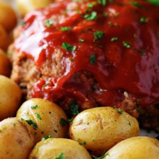 A closeup of this instant pot meatloaf with a tomato glaze and baby potatoes